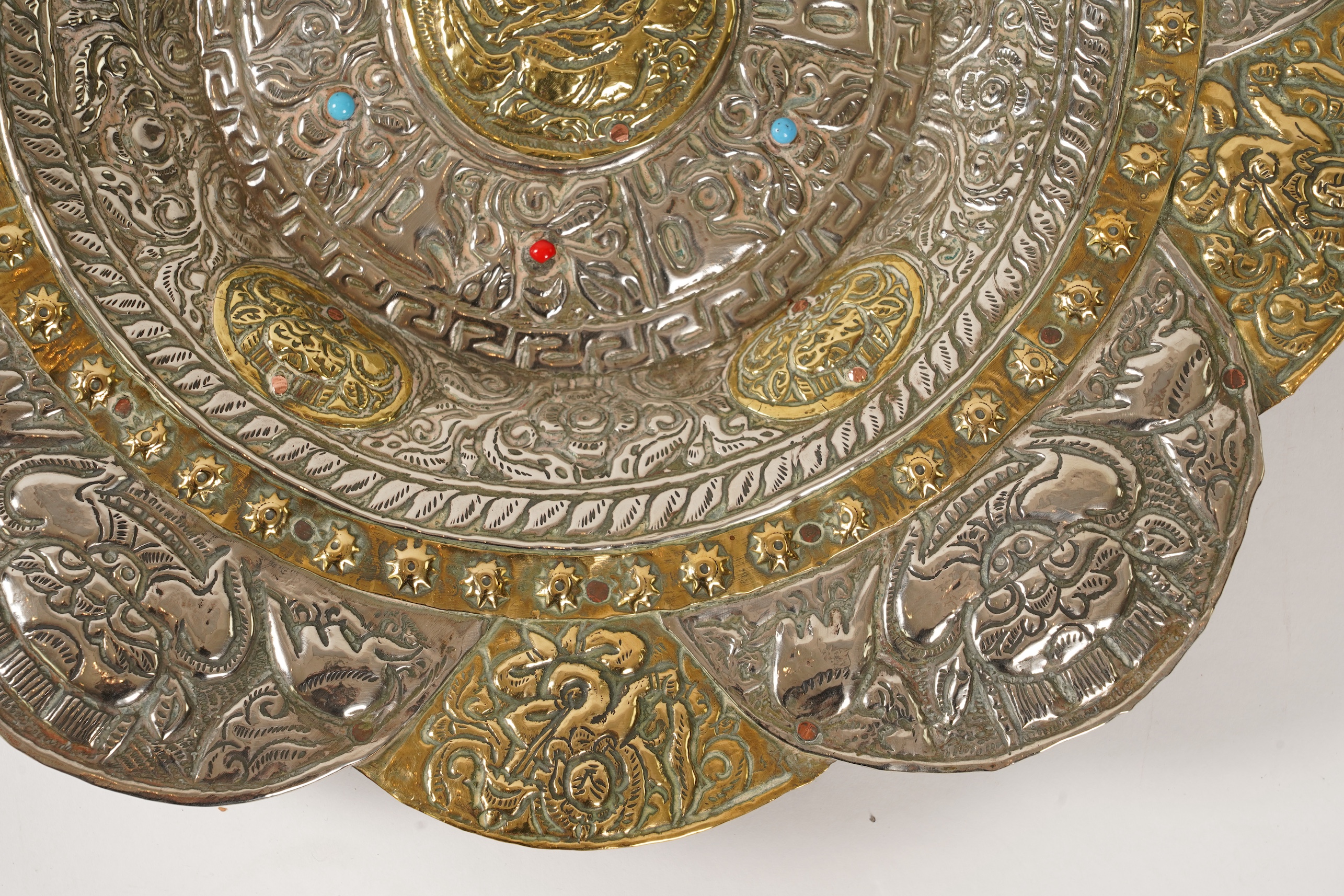 A graduated set of three Nepalese repoussé white metal and brass chargers, first half 20th century